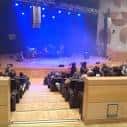 Escenario con iluminación azul y público en el auditorio