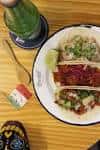 Primer plano de tacos y bebida en mesa de madera