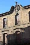 Primer plano vertical del escudo y ventanas superiores de Casa Cornide