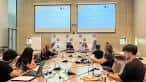Sala de conferencias con asistentes y dos pantallas de proyección durante un simposio