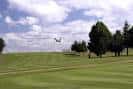 Campo de golf con un avión en el cielo, reflejando la actividad del aeroclub