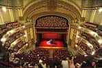 Interior del teatro con público y un artista en el escenario