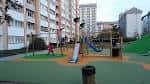 Parque infantil moderno con edificios residenciales al fondo en Elviña