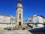 Antigua torre del reloj de piedra en una plaza soleada