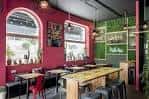 Interior del restaurante con mesas, decoración vibrante y grandes ventanales