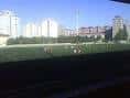 Vista del campo de fútbol exterior del complejo deportivo con edificios residenciales al fondo