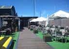 Terraza exterior de El Pantalán Rest Club con mesas y sombrillas bajo el sol