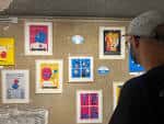 Persona observando obras de arte enmarcadas expuestas en la pared de la galería