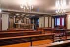 Capilla o salón de actos con bancos de madera y candelabros