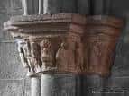 Primer plano de un capitel esculpido con figuras en el interior de la iglesia.