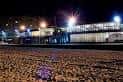 Fachada del Playa Club iluminada por la noche desde la playa