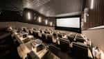 Sala de cine premium con butacas claras y pantalla de proyección