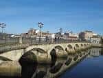 Vista del Puente del Burgo con el río y la ciudad al fondo bajo cielo azul