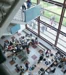 Interior de un vestíbulo o sala común con grandes ventanales y estudiantes