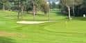 Green y bunker del campo de golf rodeado de árboles