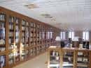 Interior de la biblioteca con estanterías de madera y mesas de estudio