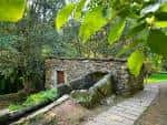 Antiguo molino de piedra con canal de agua y sendero en el entorno natural del Parque Forestal de Zamáns.