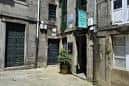 Callejón estrecho con edificios de piedra y vegetación en Santiago de Compostela