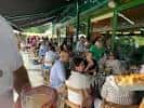 Terraza exterior cubierta con personas disfrutando de un evento o comida.