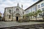 Vista frontal de la Colegiata de Santa María del Campo y la plaza empedrada en un día nublado.