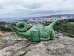 Escultura de dragón verde con vistas a la ciudad de Santiago desde el Monte do Viso