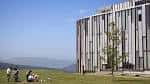 Edificio universitario moderno con estudiantes en el césped
