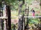 Persona en un puente colgante de madera en el parque de aventuras