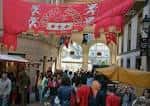 Calle decorada con estandartes rojos y puestos de la Feira das Marabillas