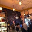 Interior animado de la taberna con barra y pizarra de especialidades
