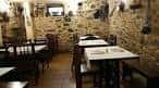 Salón rústico de un restaurante con paredes de piedra y mobiliario de madera en Vigo