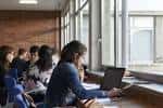 Aula universitaria con estudiantes y grandes ventanales