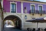 Detalle del arco y el edificio morado con mesas de terraza en la Plaza Méndez Núñez