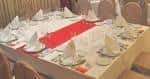 Detalle de mesa con mantel blanco y camino de mesa rojo