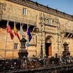 Entrada monumental del Hostal dos Reis Católicos con banderas en la Praza do Obradoiro