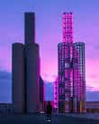 Torres Hejduk iluminadas en tonos morados al anochecer en la Cidade da Cultura