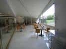 Cafetería interior del CGAC con mesas y sillas, junto a grandes ventanales.