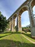 Vista del Viaducto de A Chanca desde abajo, con arcos de piedra y vegetación.