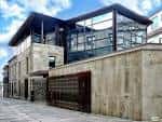 Entrada moderna del museo con fachada de piedra y cristal