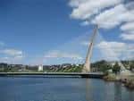 Puente de los Tirantes bajo un cielo azul con nubes, visto desde el río
