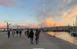 Gente paseando por el Paseo Marítimo de A Coruña junto a la marina al anochecer