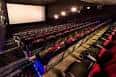 Interior de sala de cine con butacas rojas y pantalla