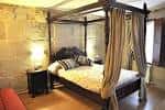 Habitación de hotel con cama con dosel y pared de piedra vista