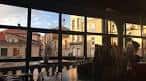 Interior del café cultural con grandes ventanales que ofrecen vistas a la arquitectura circundante de Ourense