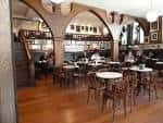 Interior del Café Latino con mesas, sillas y escalera de madera