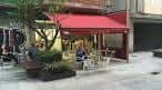 Exterior de un bar con toldo rojo y terraza en Vigo
