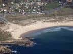 Playa curva de Doniños desde el aire con zona urbana cercana