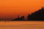 Silueta de la Illa de Tambo y su faro al atardecer con cielo anaranjado