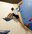 Deportista escalando una pared de búlder en un rocódromo
