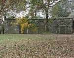 Muro de piedra con arcos y vegetación en una zona verde del parque
