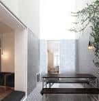 Patio interior o sala con mesa larga, bancos y paredes con diseño geométrico